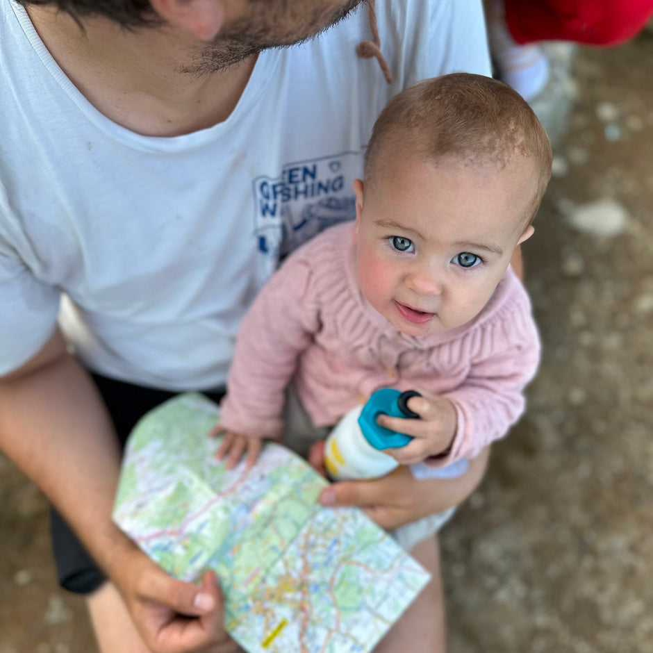 Dad holds baby and card, baby looks at camera