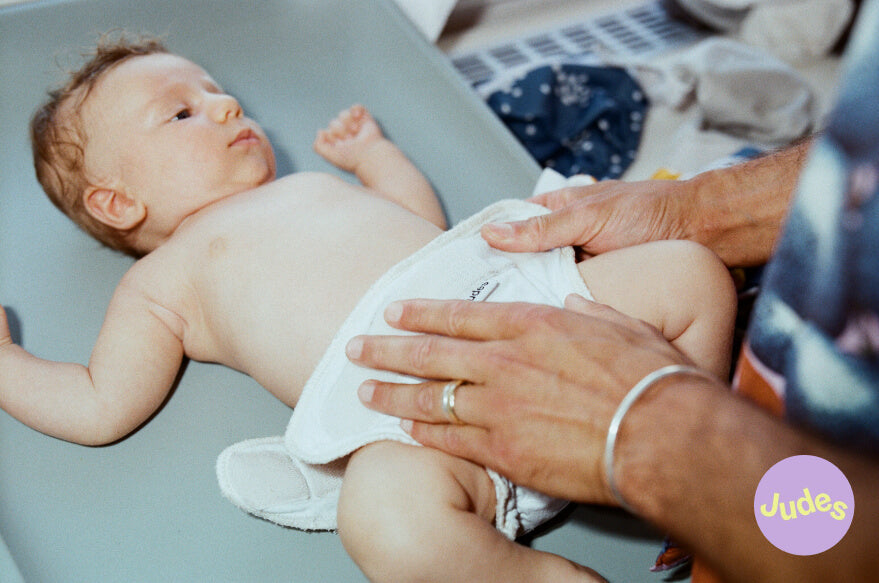 Baby is being diapered with a Judes cloth diaper.